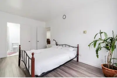 a bedroom with a bed with white sheets and a potted plant at Comfortable 4B Unit-Close to City Attractions in Montréal