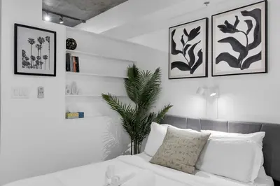 a bedroom with white walls and a bed with white pillows at Dreaming at the Base of the Mountain With Parking in Montréal