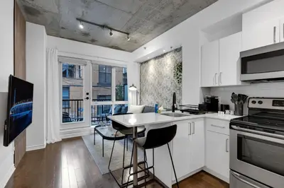 a kitchen with white cabinets and a table and chairs at Dreaming at the Base of the Mountain With Parking in Montréal