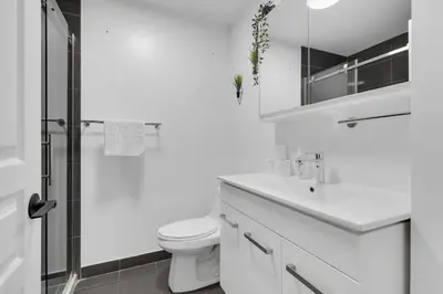 a white bathroom with a toilet and a sink at Dreaming at the Base of the Mountain With Parking in Montréal