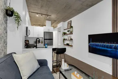 a living room with a blue couch and a kitchen at Dreaming at the Base of the Mountain With Parking in Montréal
