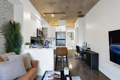 a living room with a couch and a kitchen at Pristine Parc Avenue Pad With Parking in Montréal