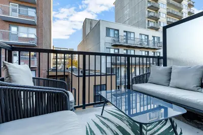 a balcony with a couch and a glass table at Pristine Parc Avenue Pad With Parking in Montréal