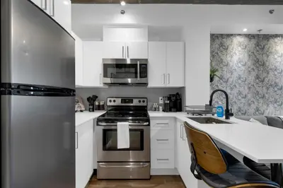 a kitchen with white cabinets and stainless steel appliances at Impeccable Parc Avenue Pad With Parking in Montréal