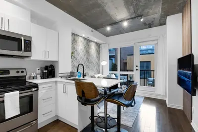 a kitchen with white cabinets and a table with chairs at Impeccable Parc Avenue Pad With Parking in Montréal