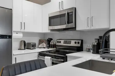 a kitchen with white cabinets and a stove top oven at Impeccable Parc Avenue Pad With Parking in Montréal