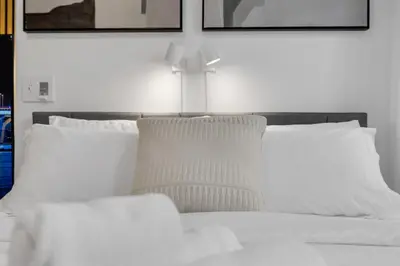 a white bed with two pillows and a cross on it at The Sherbrooke Suite 101 in Montréal