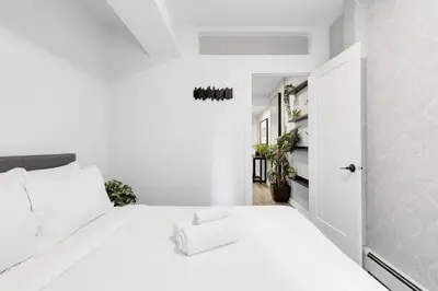 a white bedroom with a white bed with white pillows at The Sherbrooke Suite in Montréal
