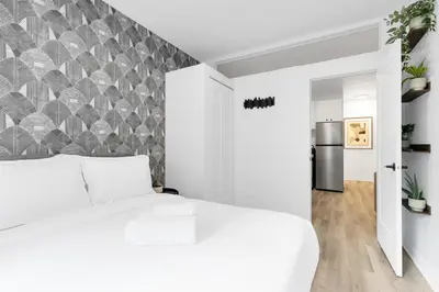 a bedroom with a white bed and a wall at The Sherbrooke Suite in Montréal