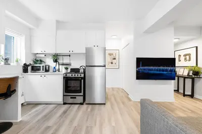a kitchen with white cabinets and a stainless steel refrigerator at The Sherbrooke Suite in Montréal