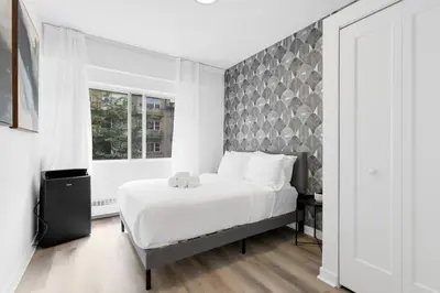 a bedroom with a large white bed and a window at The Sherbrooke Suite in Montréal