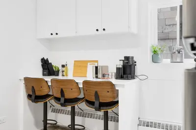 a kitchen with a counter with two chairs at a table at The Sherbrooke Suite in Montréal