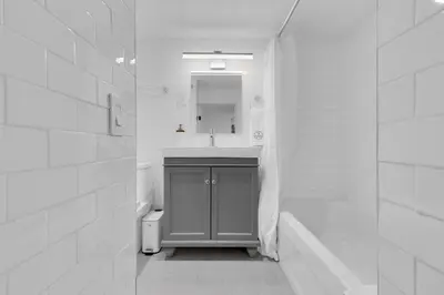 a white bathroom with a sink and a mirror at The Sherbrooke Suite 105 in Montréal