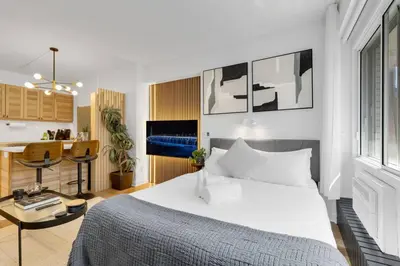 a bedroom with a large white bed and a kitchen at The Sherbrooke Suite 99 in Montréal