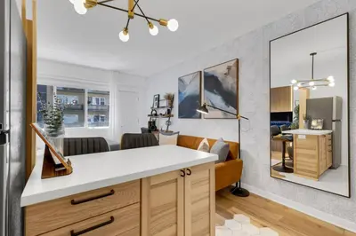 a kitchen with a white counter and a living room at The Sherbrooke Suite 99 in Montréal