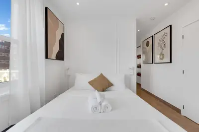 a white bedroom with a large white bed with two slippers at The Speakeasy Suite 501 With Parking in Montréal