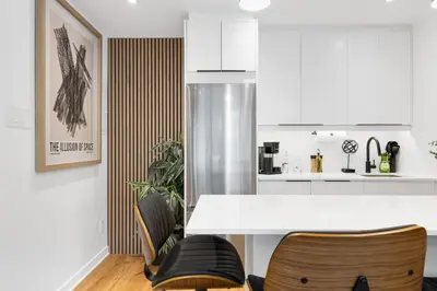 a kitchen with a white counter and some chairs at Atelier Montreal Luxe 1BR King Bed With Parking in Montréal
