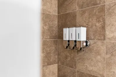 a shower with a tile wall with a soap dispenser at Downtown Montreal Horizon Suite With Parking in Montréal