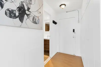 a hallway with white walls and a white door with a painting at Downtown Montreal Horizon Suite With Parking in Montréal