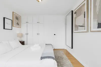 a white bedroom with a white bed and framed pictures at Downtown Montreal Horizon Suite With Parking in Montréal