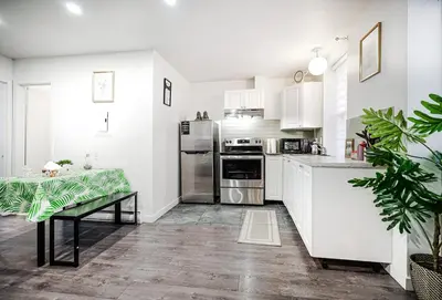 a kitchen with white cabinets and a table in it at Appartement design au cœur de Griffintown in Montréal