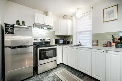 a kitchen with white cabinets and stainless steel appliances at Appartement design au cœur de Griffintown in Montréal