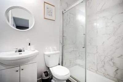 a white bathroom with a shower and a toilet and a sink at Appartement design au cœur de Griffintown in Montréal