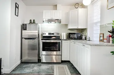 a kitchen with white cabinets and stainless steel appliances at Appartement design au cœur de Griffintown in Montréal