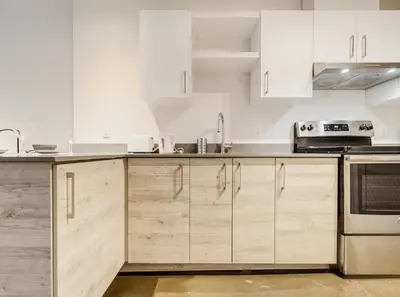 a kitchen with white cabinets and stainless steel appliances at Confort et style en plein Montréal in Montréal