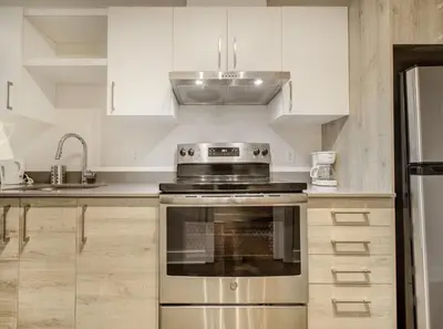 a kitchen with white cabinets and a stainless steel oven at Confort et style en plein Montréal in Montréal