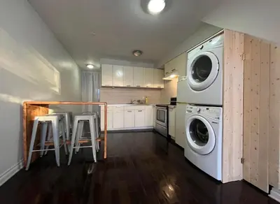 a kitchen with a washer and dryer and two stools at Mont roamyal in Montréal