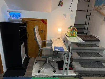 a desk and a chair in a room with stairs at Appartement Cool à Longueuil Plan A in Longueuil