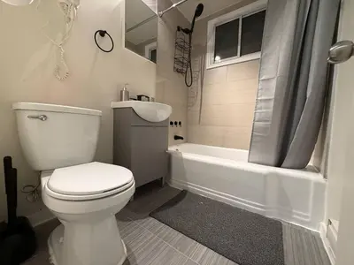 a white bathroom with a toilet and a bath tub at Lovely Vacation Home 2BR in MTL! in Montréal