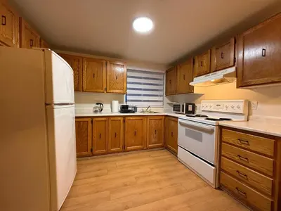 a kitchen with a white refrigerator and wooden cabinets at Free Parking! Montreal Adventure Home - Modern & Spacious Comforts! in Montréal