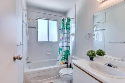 a white bathroom with a tub and a sink and a toilet at Montreal & Free Parking Comfy Cozy Pierrefonds Apts in Montréal