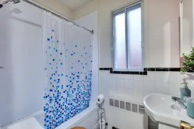 a white bathroom with a blue tile shower curtain at NDG & Montreal getaway in Montréal