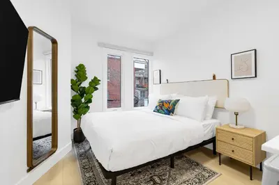 a white bedroom with a large bed and a mirror at Le Mistral Modern Studios in Montréal