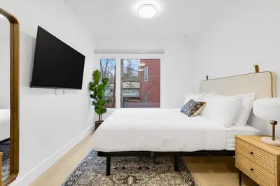a white bedroom with a bed and a mirror at Le Mistral Modern Studios in Montréal