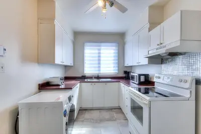a white kitchen with white appliances and a window at NDG Montreal! Attractions & Downtown Adventure Travels! Family, Friends, Work-travel! in Montréal
