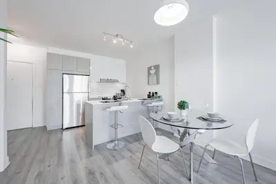 a white kitchen with a table and white chairs at Panoramic Skyline Penthouse Montreal Downtown -Free Parking - In Suite Laundry in Montréal