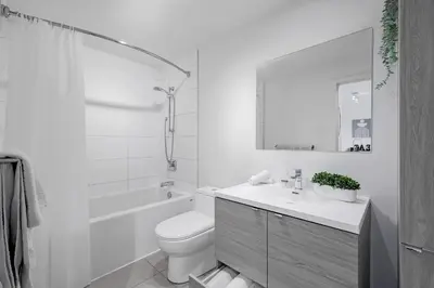 a white bathroom with a toilet and a sink at Panoramic Skyline Penthouse Montreal Downtown -Free Parking - In Suite Laundry in Montréal
