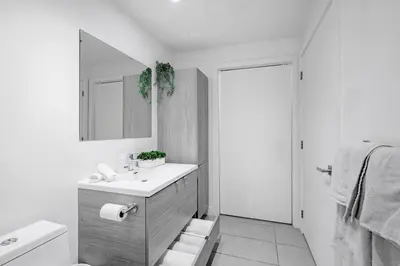 a white bathroom with a sink and a mirror at Panoramic Skyline Penthouse Montreal Downtown -Free Parking - In Suite Laundry in Montréal