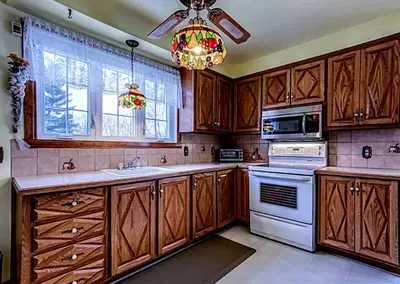 a kitchen with wooden cabinets and a chandelier at 2beds in Room A Free parking 15min to downtown in Longueuil