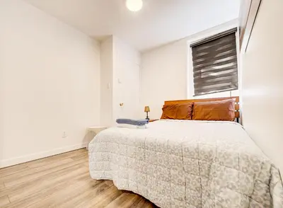 a white bedroom with a bed and a window at Appartement design au cœur de Griffintown in Montréal