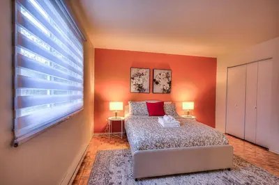a bedroom with orange walls and a bed with red pillows at Free Parking! Montreal Comfort Value Convenience! Full Kitchen, Fast Wifi, Workspace, Smart TV! in Montréal