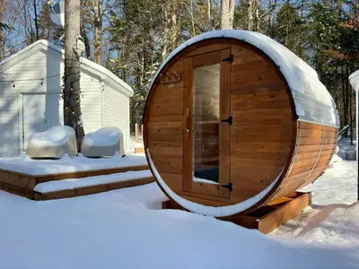 a wooden sauna in the snow next to a building at Pur Nature Garthby et Sauna in Saint-Gérard