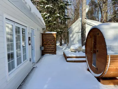 a snow covered yard next to a house with a sauna at Pur Nature Garthby et Sauna in Saint-Gérard