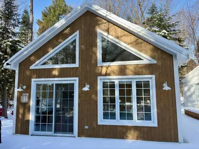 a house with three windows in the snow at Pur Nature Garthby et Sauna in Saint-Gérard