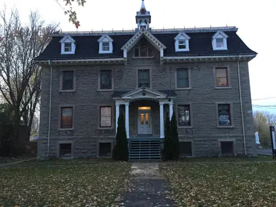 an old brick house with a clock tower on top at Le Loft des Milles-Îles in Laval