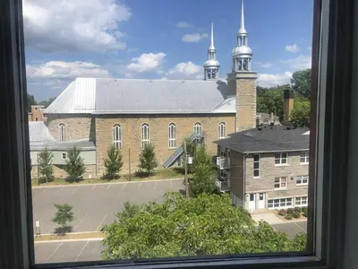 a view of a large brick building with a church at Le Loft des Milles-Îles in Laval